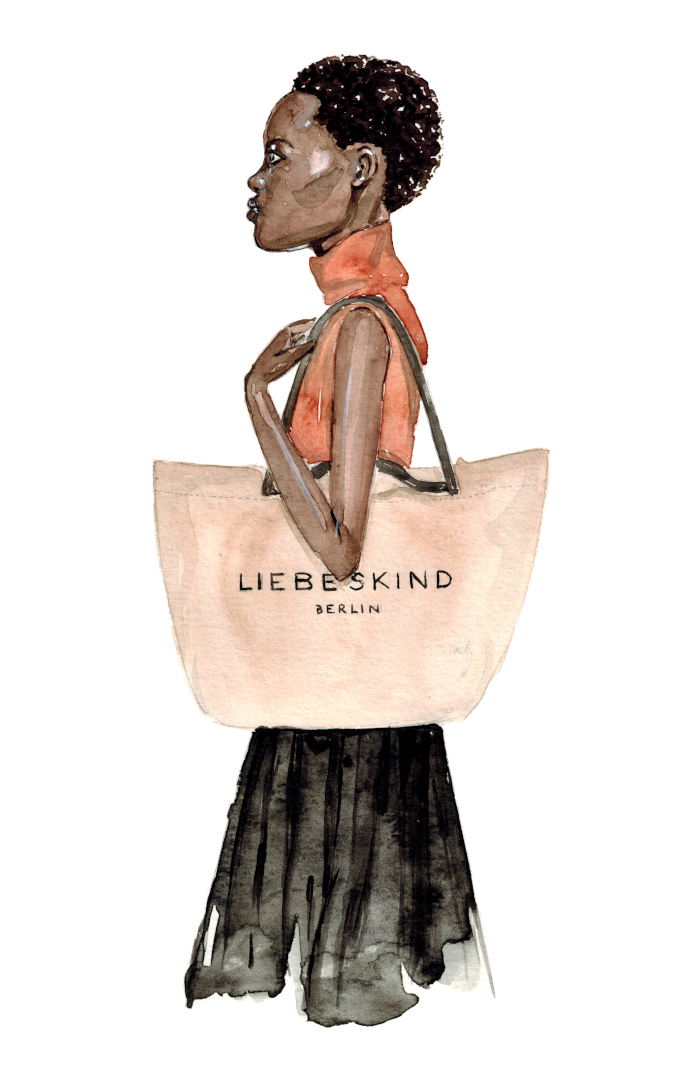 schwarze Frau mit kurzen Haaren trägt einen beigen Shopper in Liebeskind über ihrer Schulter und trägt dabei einen hellbraunen Rollkragenpullunder und einen schwarzen Rock